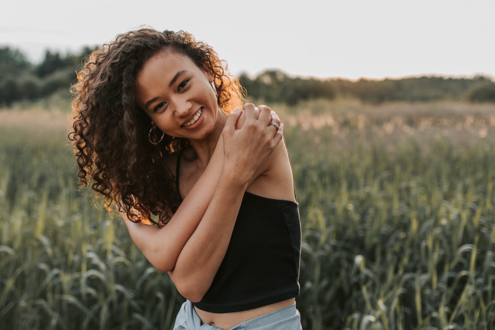 Women with curl in a field during sunset