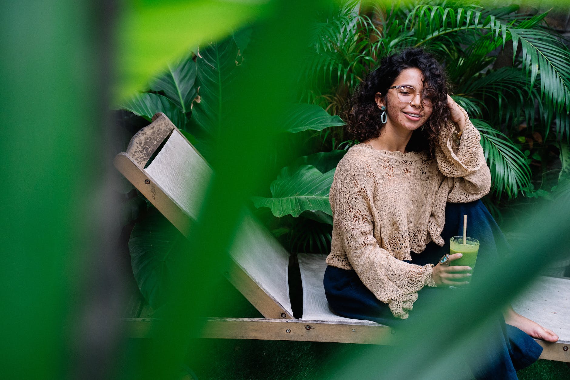 Woman with curls and skin condition sitting between plants