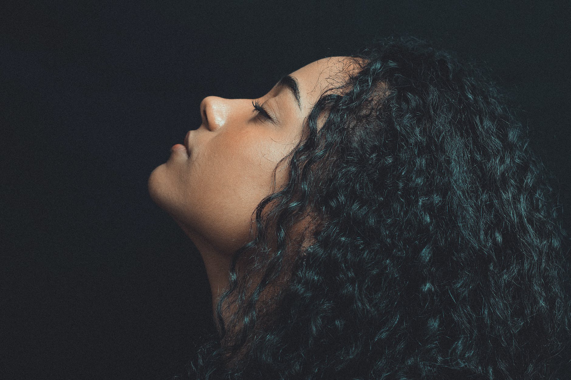 coloured curly haired woman with black background